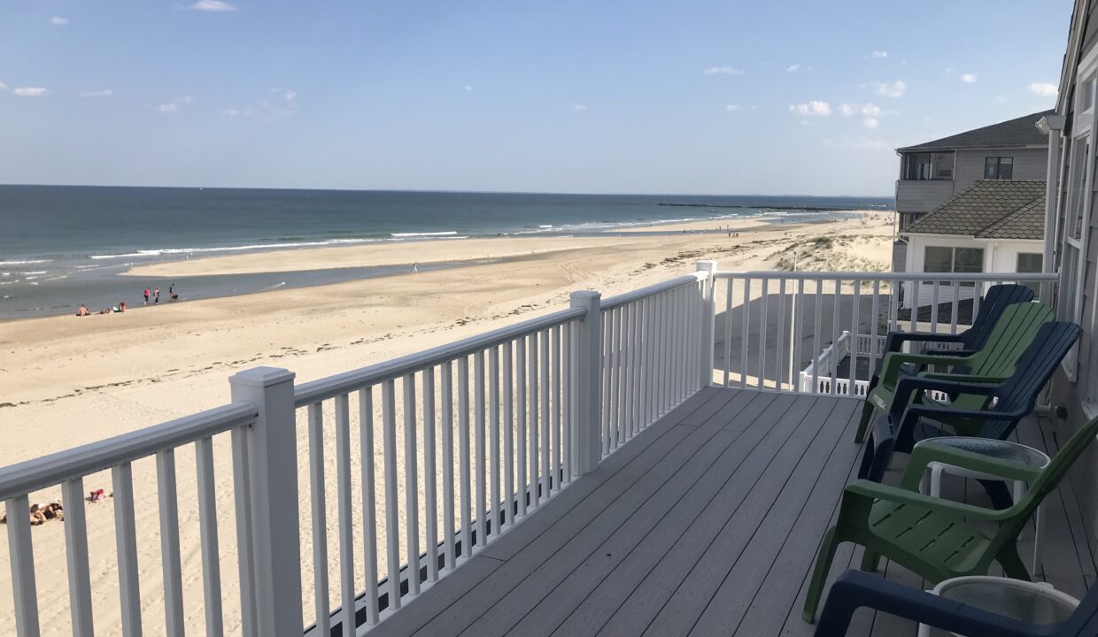 a couple of lawn chairs sitting on top of a wooden deck.