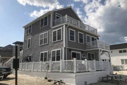 a beach house with a deck and a car parked in front of it.