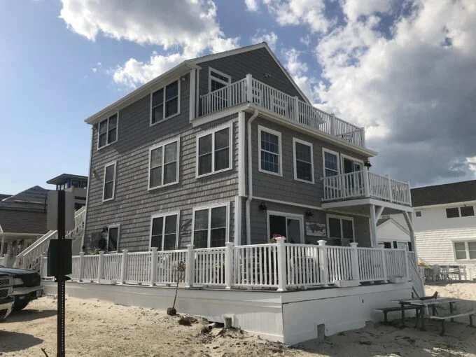 a beach house with a deck and a car parked in front of it.