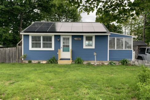 a small blue house with a metal roof.