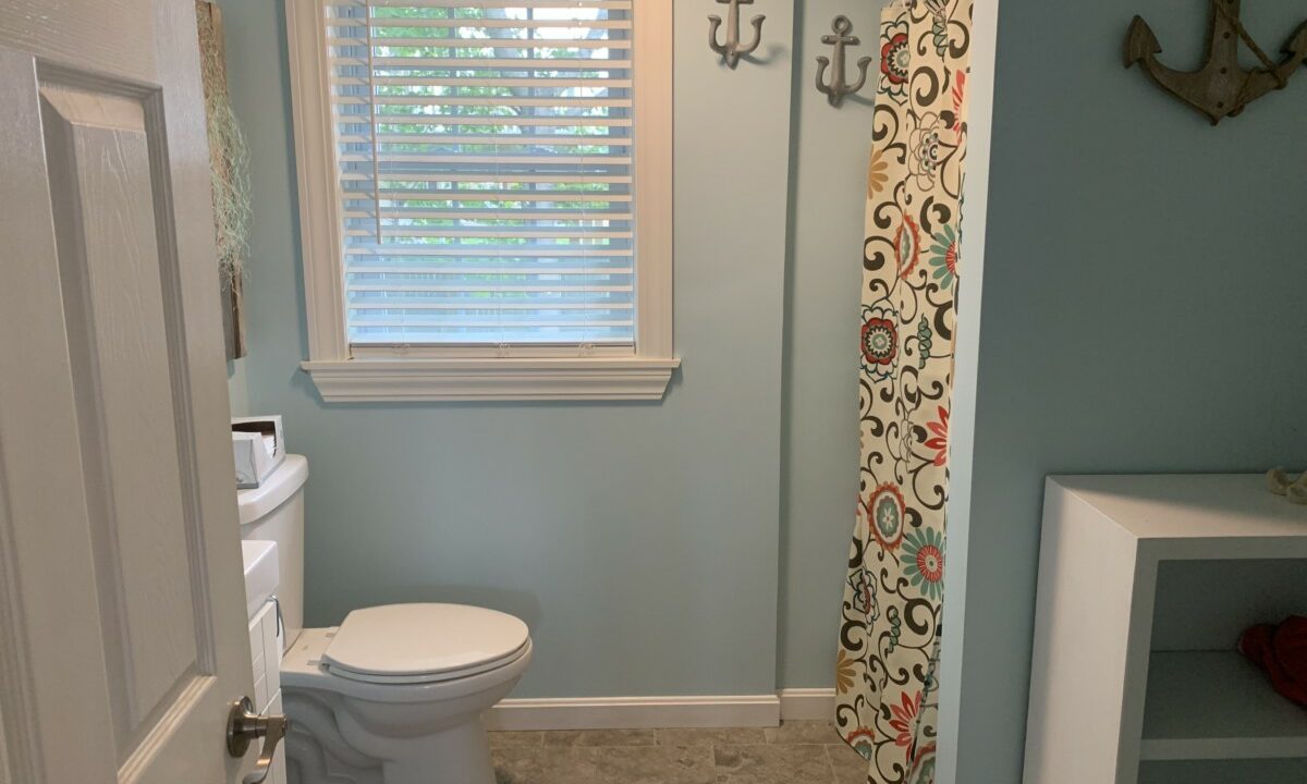 a white toilet sitting next to a window in a bathroom.