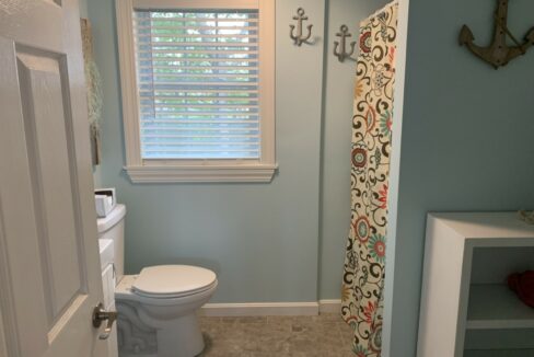 a white toilet sitting next to a window in a bathroom.