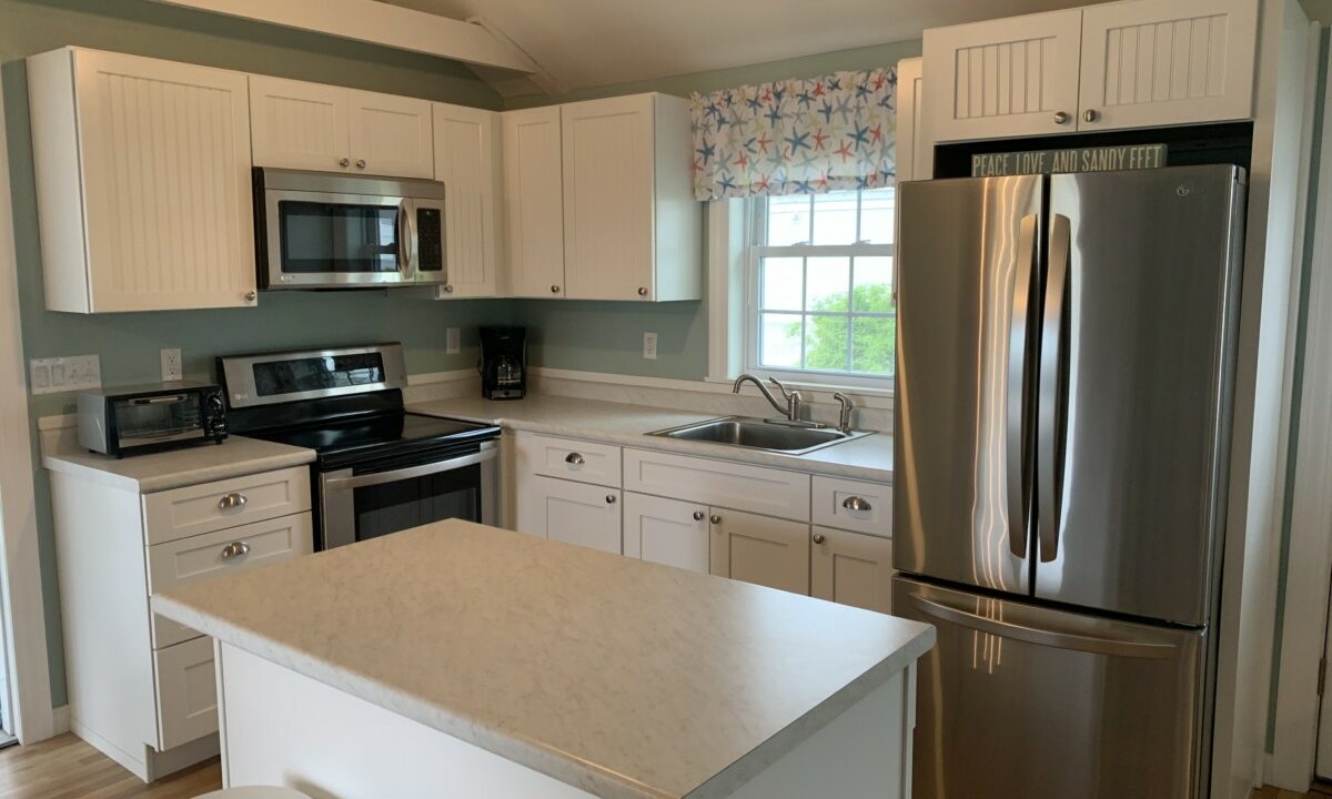 a kitchen with a refrigerator, stove, sink, and stools.