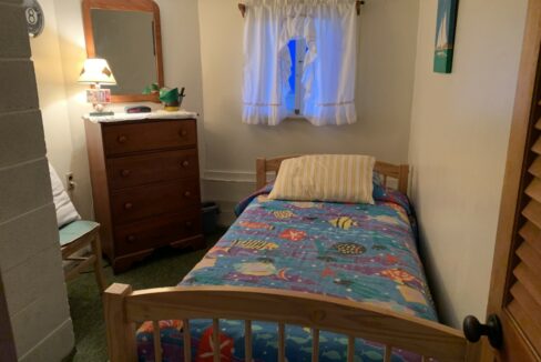 a bedroom with a bed, dresser and mirror.