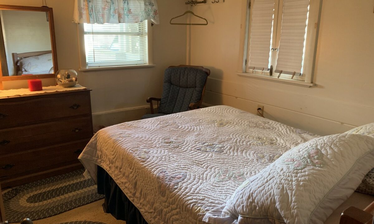 a bedroom with a bed, dresser, and chair.
