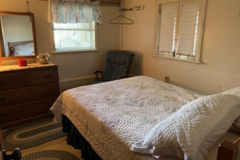 a bedroom with a bed, dresser, and chair.