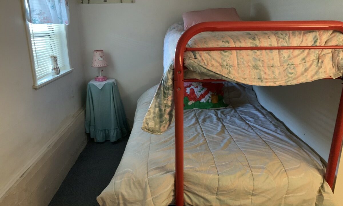 a red metal bunk bed sitting in a bedroom next to a window.