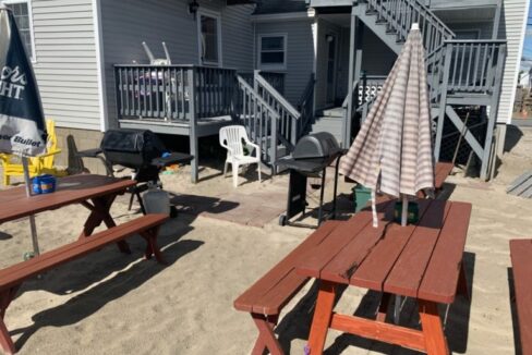 a group of picnic tables sitting on top of a sandy beach.