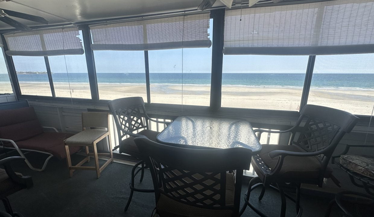 a table and chairs in a room with a view of the ocean.