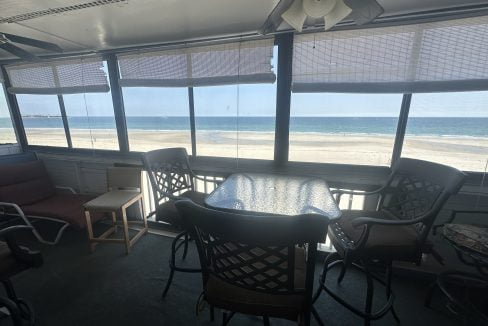 a table and chairs in a room with a view of the ocean.