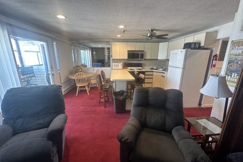 a living room with a red carpet and chairs and a table.