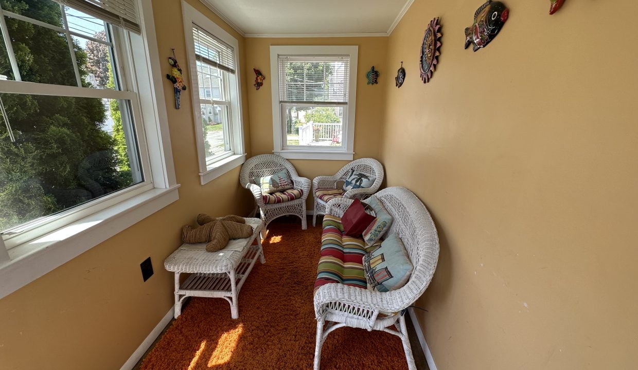 a room with white wicker furniture and orange rug.