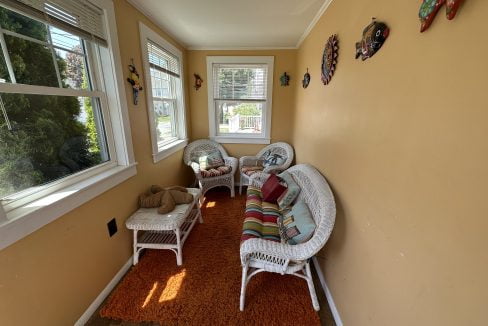 a room with white wicker furniture and orange rug.