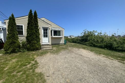 a dirt road in front of a house.