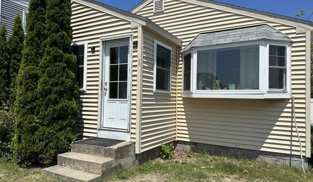 a tan house with a white door and windows.