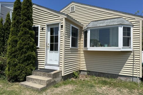 a tan house with a white door and windows.