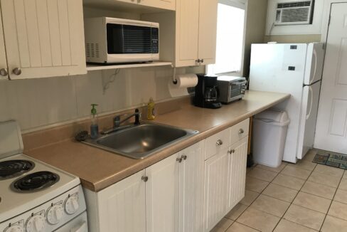 a kitchen with a sink, stove, microwave and refrigerator.