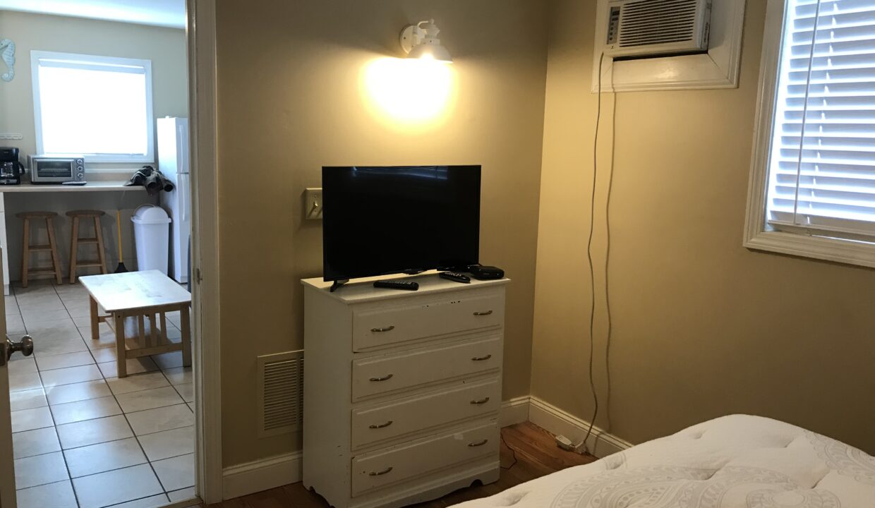 a bedroom with a bed, dresser and television.
