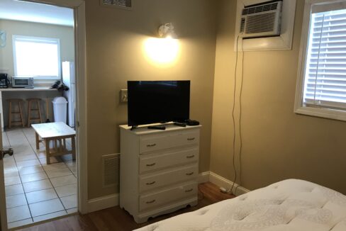 a bedroom with a bed, dresser and television.