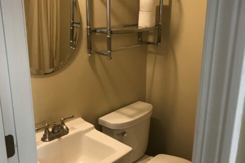 a bathroom with a toilet, sink and mirror.