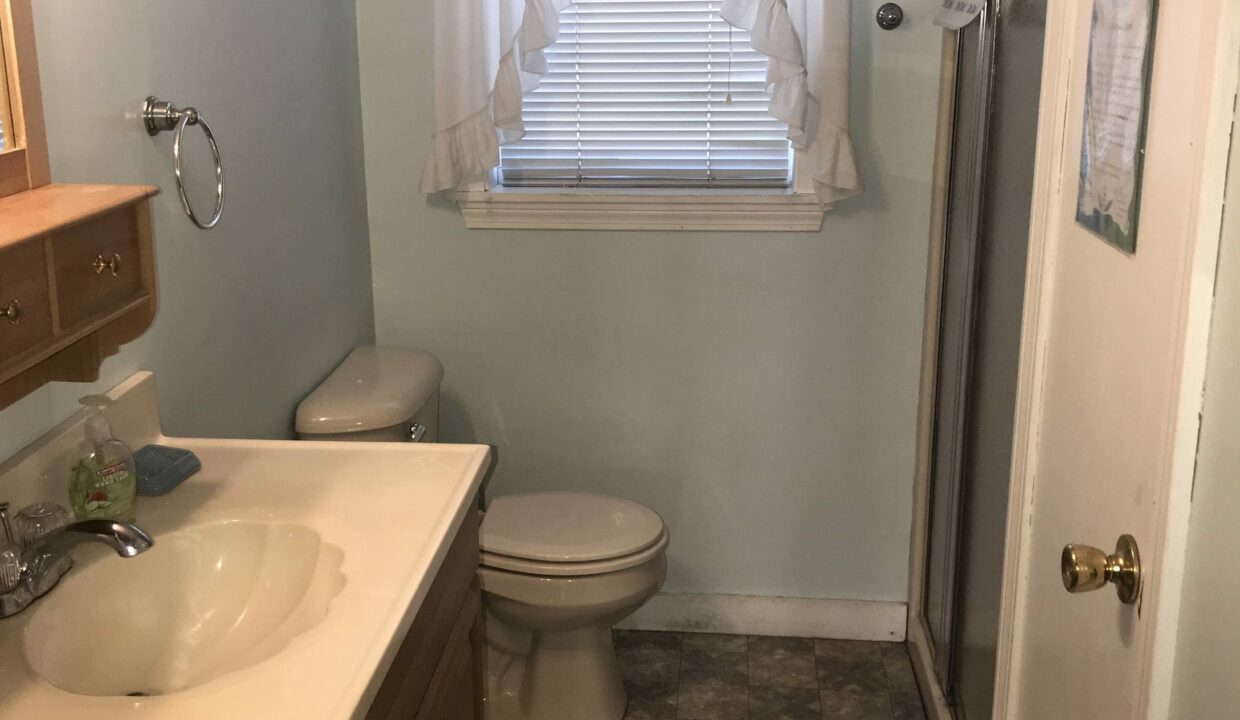 a bathroom with a sink, toilet and a window.