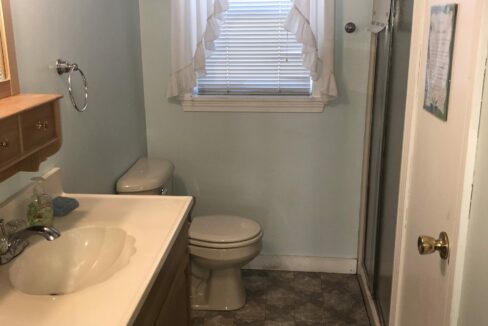 a bathroom with a sink, toilet and a window.