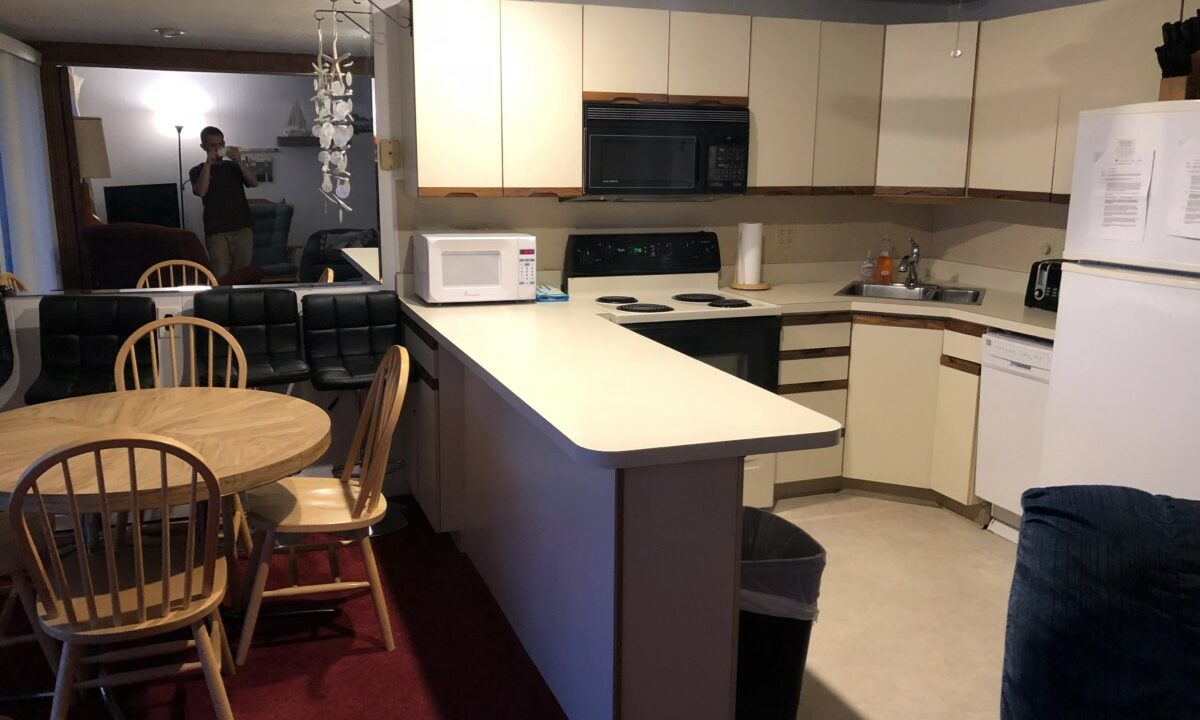 a kitchen with a refrigerator, stove, microwave and table.