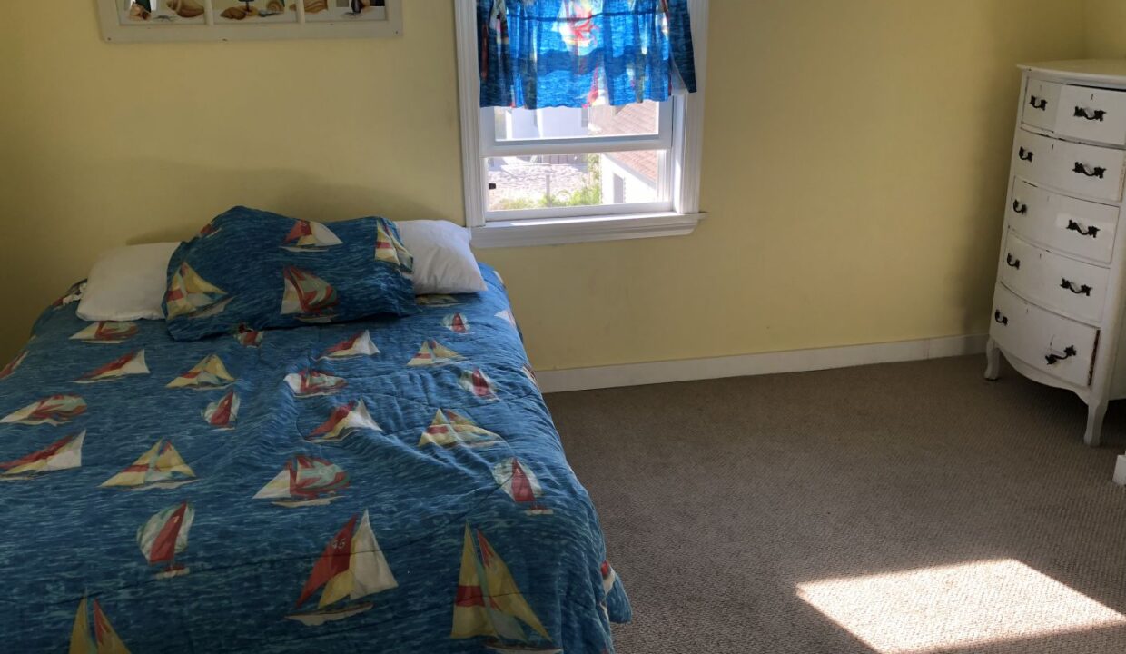 a bedroom with a bed, dresser and window.