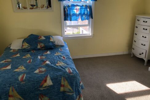 a bedroom with a bed, dresser and window.