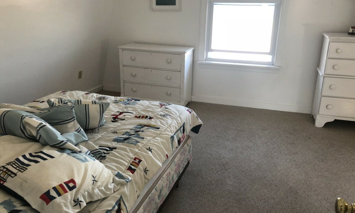 a bedroom with a bed, dresser, and window.