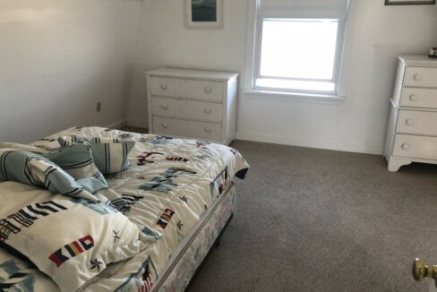 a bedroom with a bed, dresser, and window.