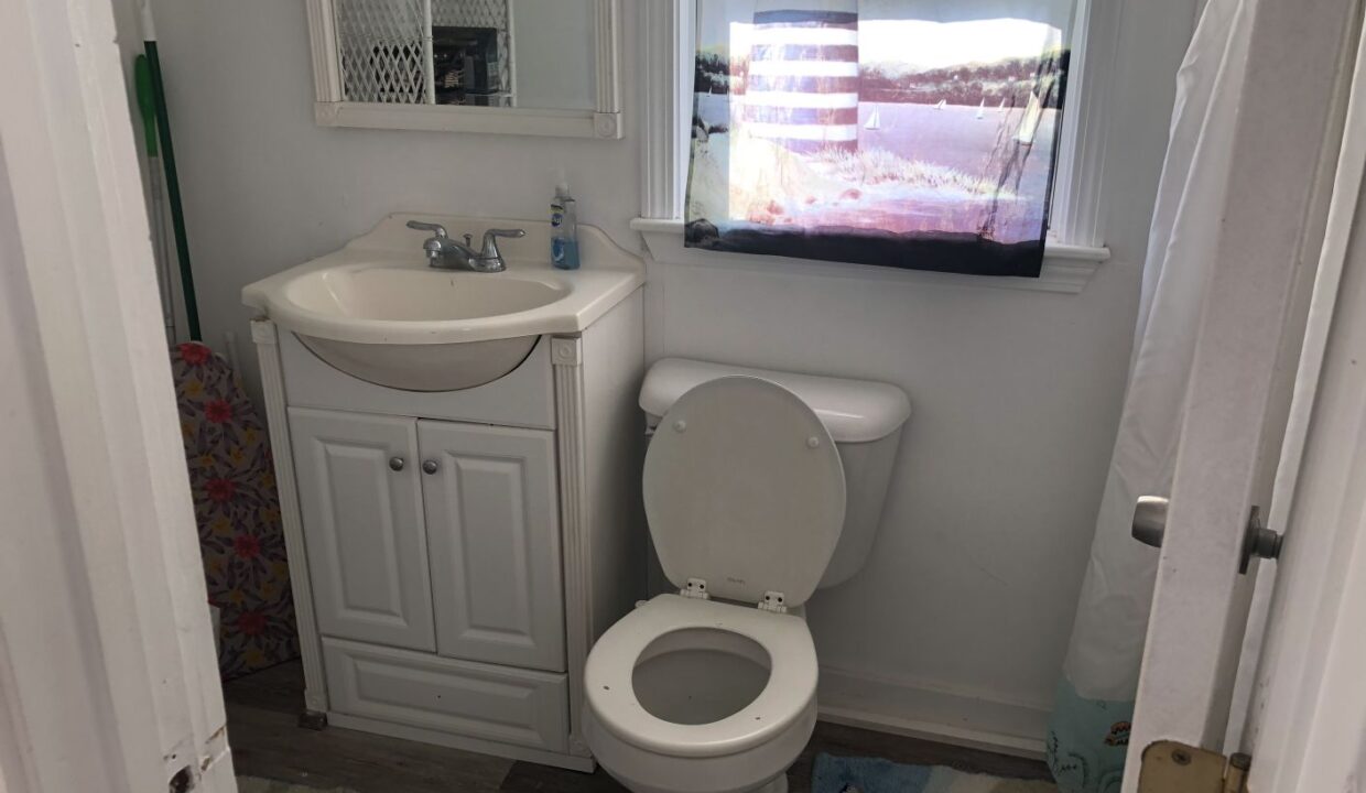 a bathroom with a toilet, sink and mirror.