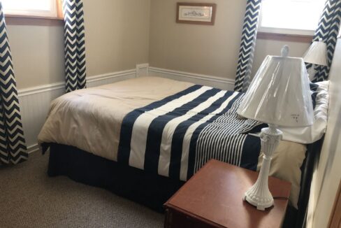 a bed room with a neatly made bed and a night stand.