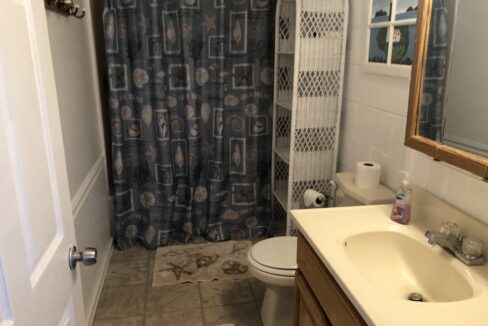 a bathroom with a toilet, sink, and shower curtain.