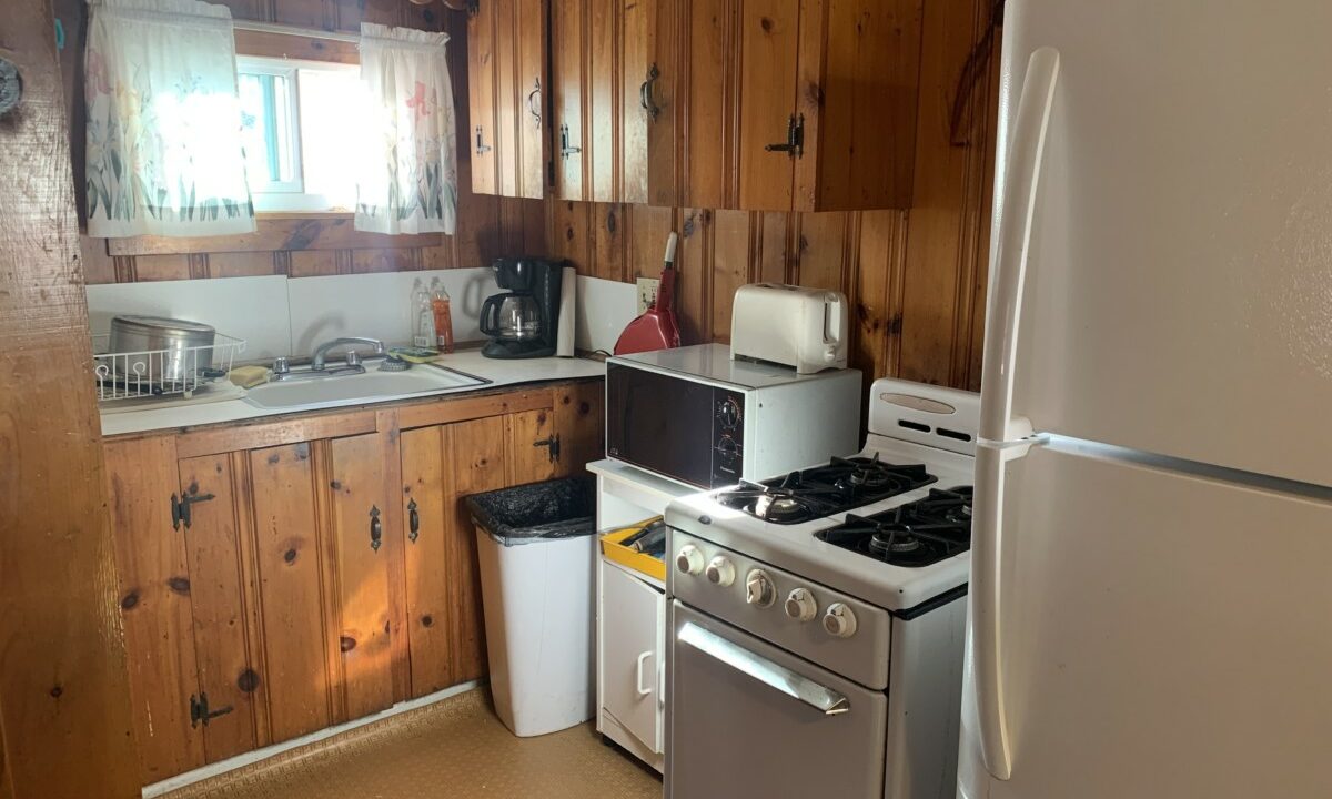 a kitchen with a stove, refrigerator, and a window.