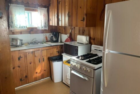 a kitchen with a stove, refrigerator, and a window.