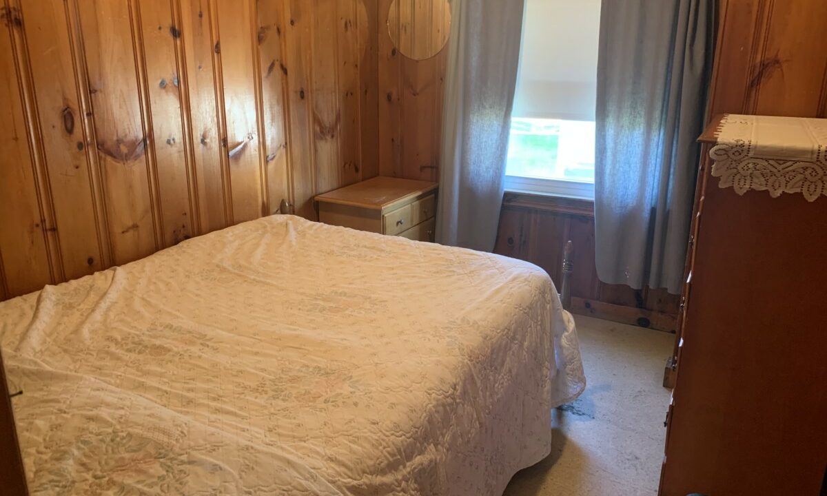 a bedroom with wood paneling and a white bed.