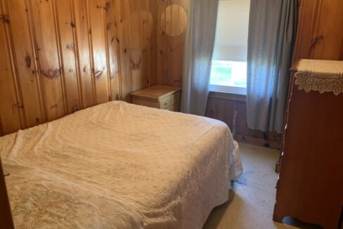 a bedroom with wood paneling and a white bed.
