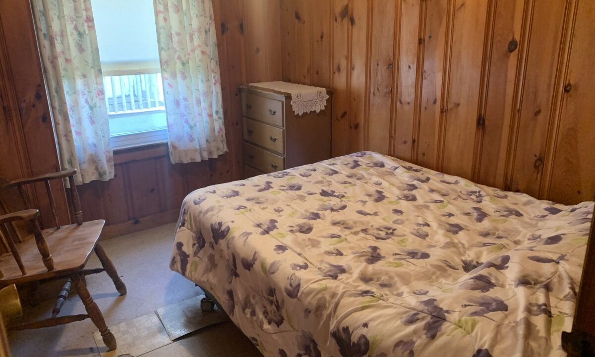 a bedroom with wood paneling and a bed.