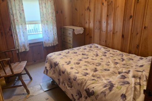 a bedroom with wood paneling and a bed.