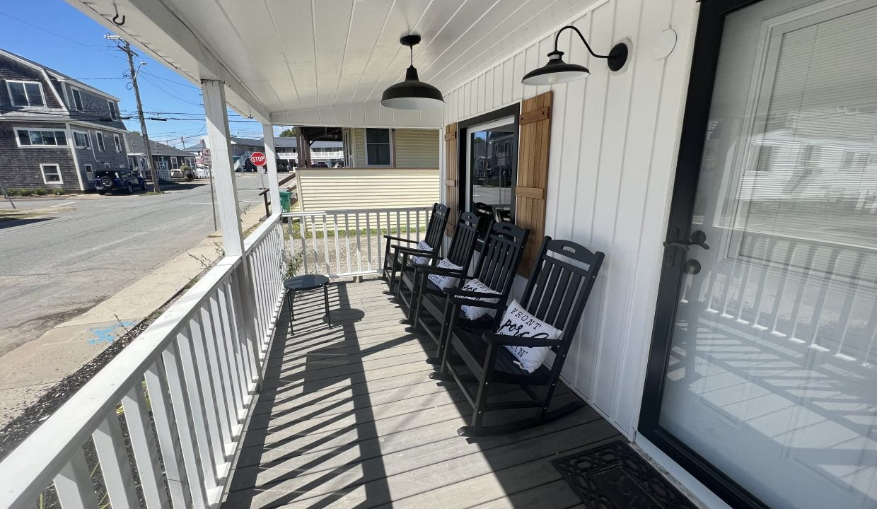 a porch with three chairs and a door.