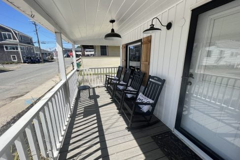 a porch with three chairs and a door.