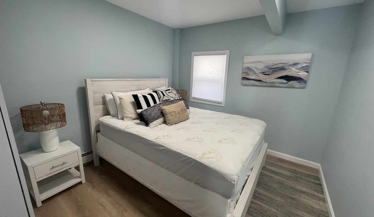 a bedroom with a bed, nightstand, and window.