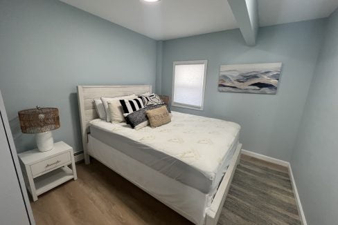 a bedroom with a bed, nightstand, and window.