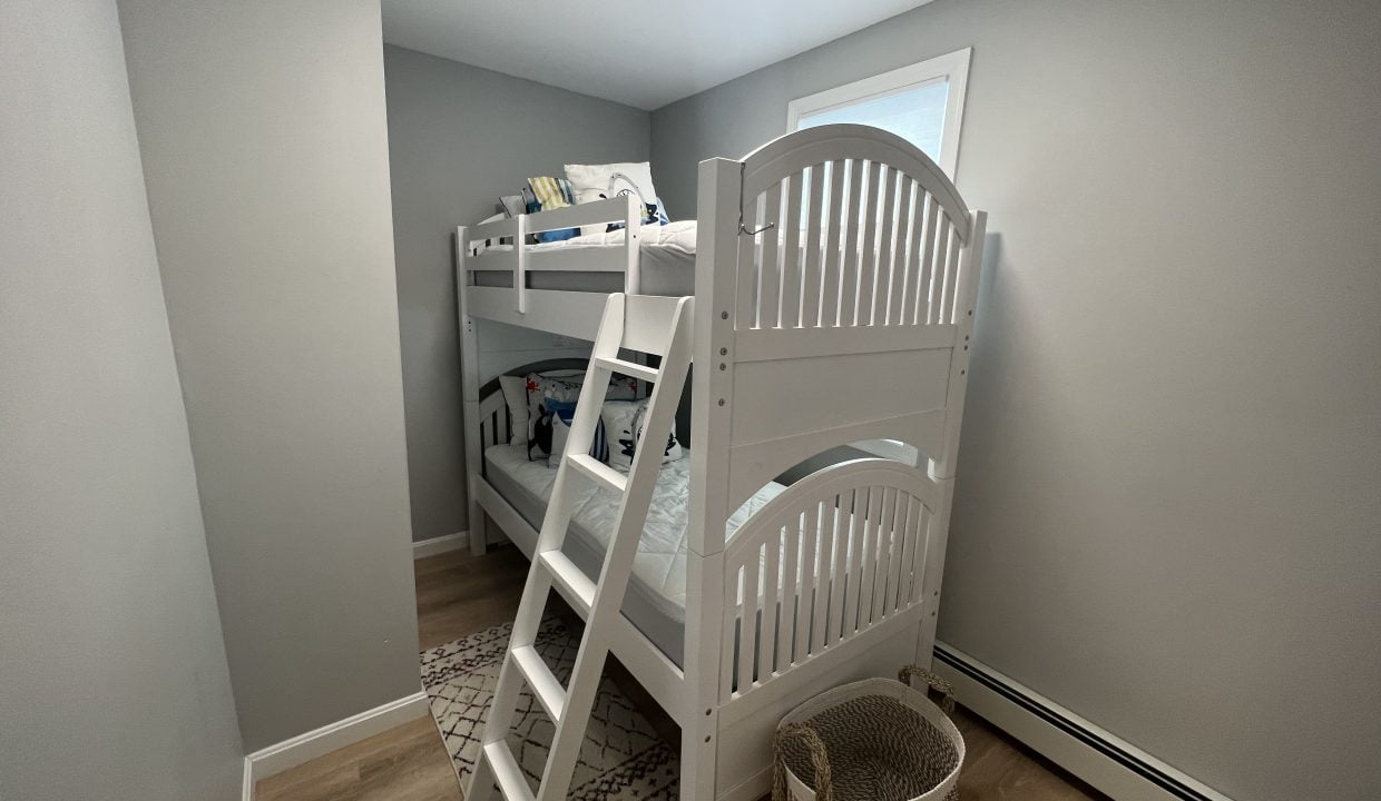 a white bunk bed sitting in a bedroom next to a window.