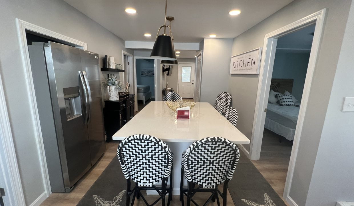 a kitchen with a refrigerator and a table with four chairs.