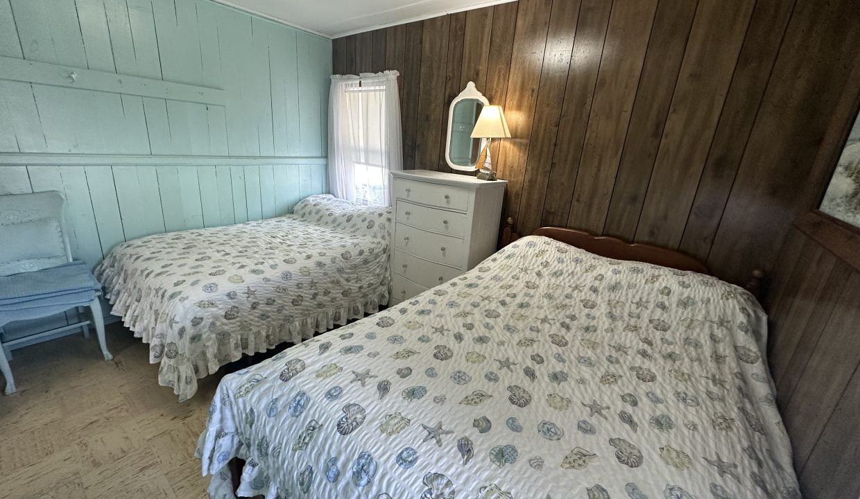 A bedroom with two beds and a dresser.