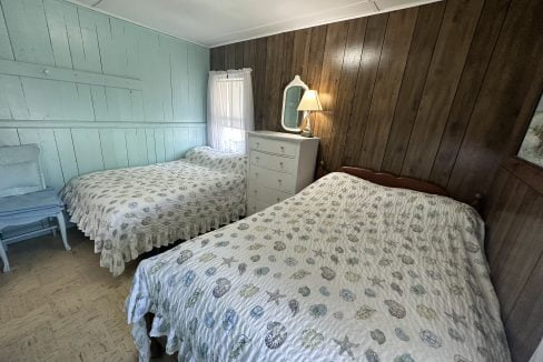 A bedroom with two beds and a dresser.