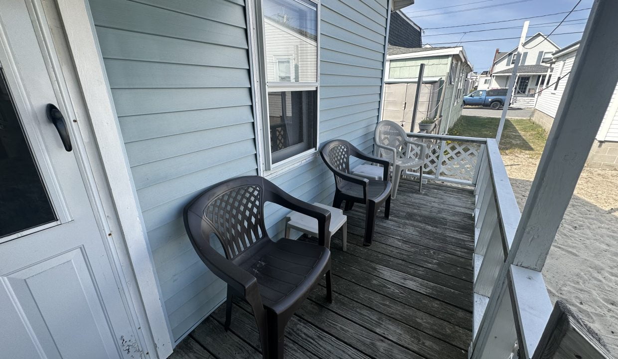 Two plastic chairs sit on the porch of a house.