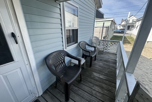 Two plastic chairs sit on the porch of a house.